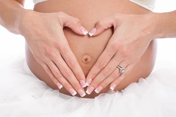 Coração em forma de mãos em uma barriga grávida — Fotografia de Stock