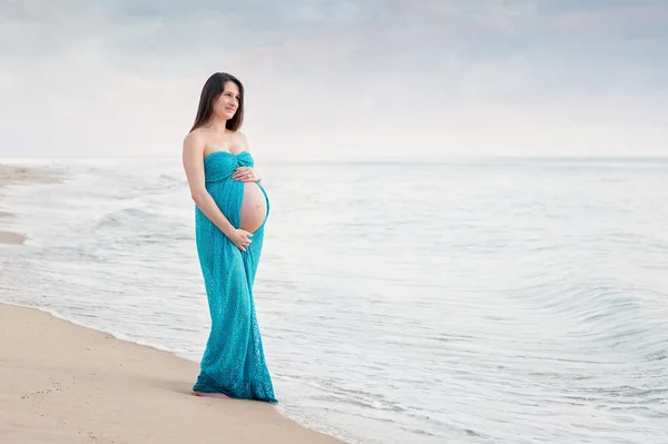 Lachende zwangere vrouw op het strand — Stockfoto