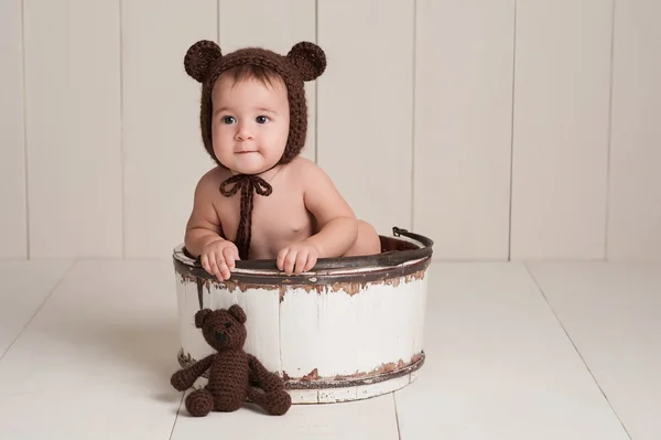 Menina bebê vestindo uma capota de urso com brinquedo de urso combinando — Fotografia de Stock