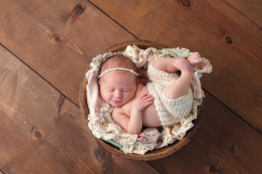 Smiling Newborn Girl Sleeping in a Wooden Bowl