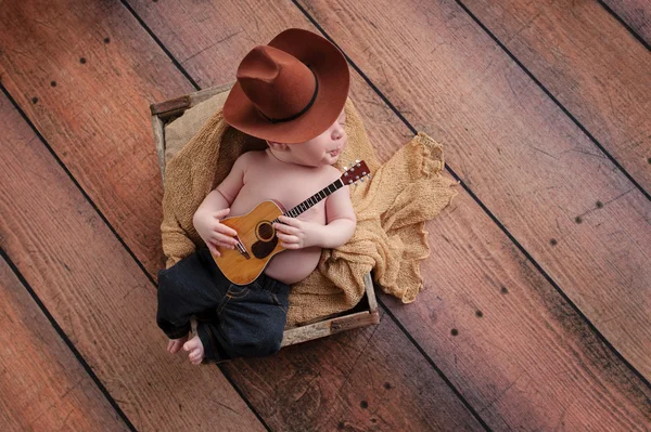 Bebé recién nacido vaquero tocando una pequeña guitarra —  Fotos de Stock