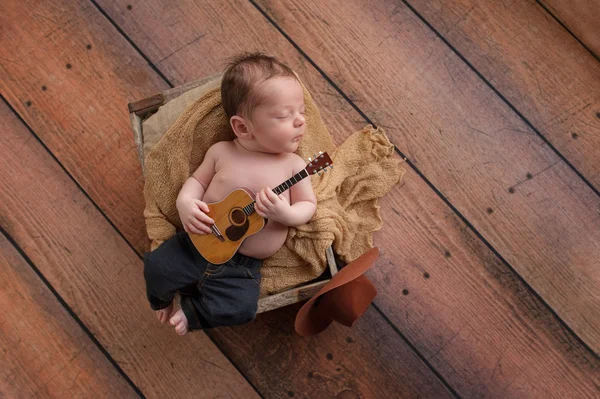 Niño recién nacido tocando una pequeña guitarra — Foto de Stock