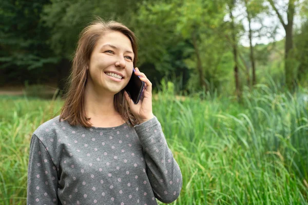 Woman talking on the phone in the park — Stock Photo, Image