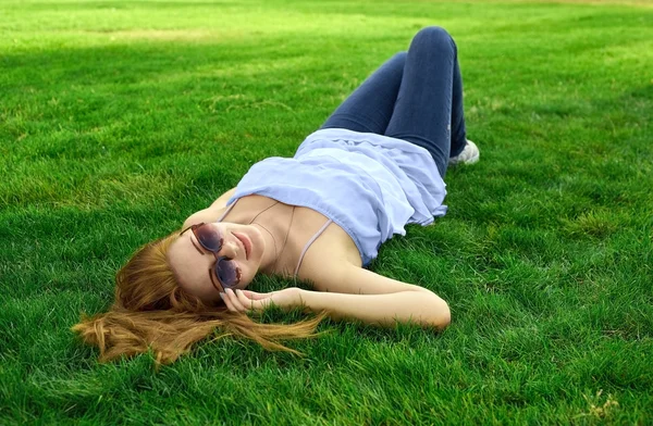 Glückliche Frau mit Brille im Gras liegend — Stockfoto