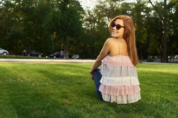 Mujer feliz con gafas sentadas en la hierba — Foto de Stock