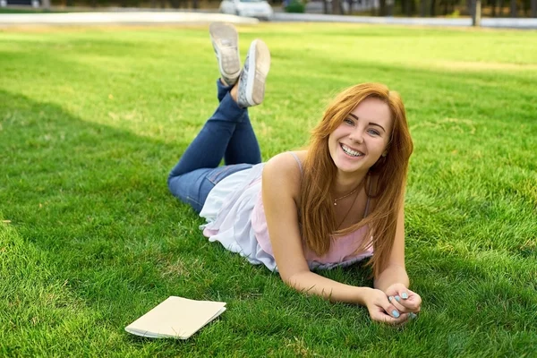 Frau liegt mit Tagebuch auf dem Rasen — Stockfoto