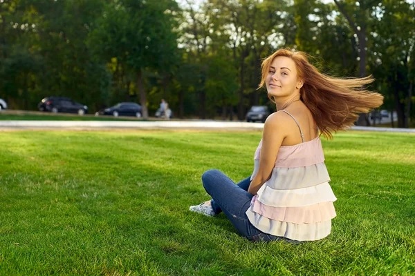 Femme heureuse assise sur la pelouse — Photo