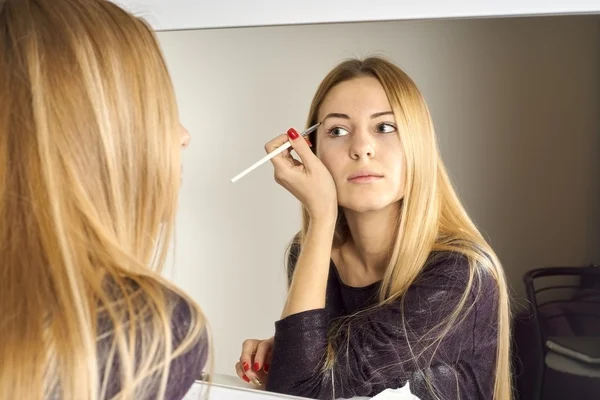 Mujer hace maquillaje ante un espejo — Foto de Stock