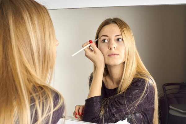 woman does makeup before a mirror