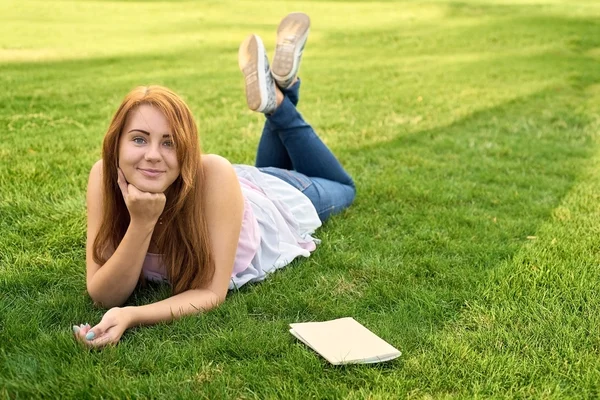 Žena leží na trávníku s deník — Stock fotografie