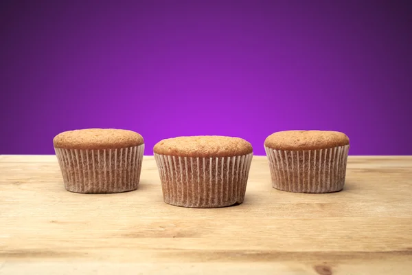 Trois cupcakes sur une table en bois — Photo