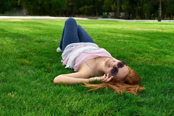 Femme heureuse avec des lunettes allongées sur l'herbe — Photo
