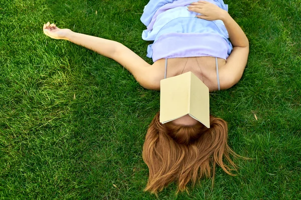 Mujer acostada en un césped con un diario — Foto de Stock