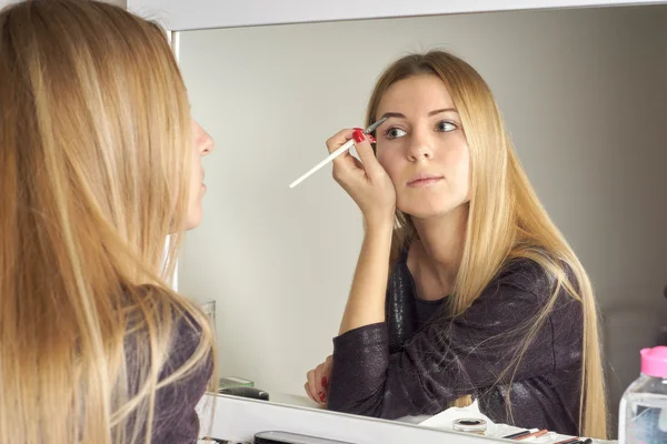 Reflejo de la joven hermosa mujer que aplica su maquillaje — Foto de Stock