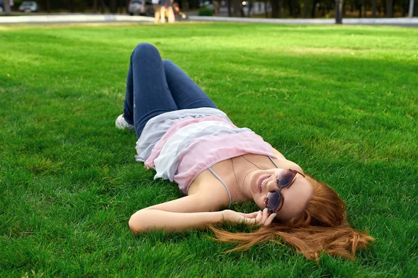 Femme heureuse avec des lunettes allongées sur l'herbe — Photo