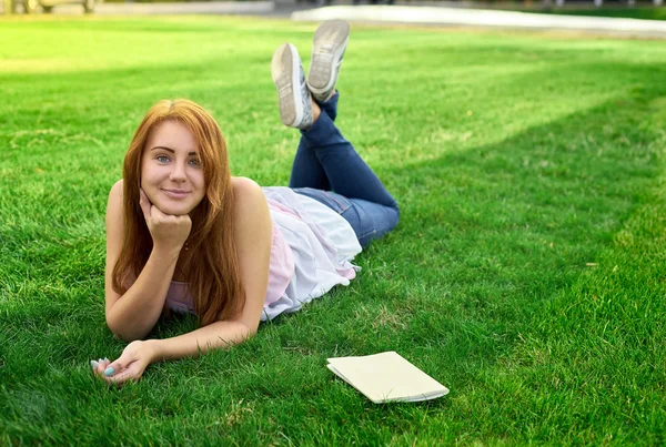 Žena leží na trávníku s deník — Stock fotografie