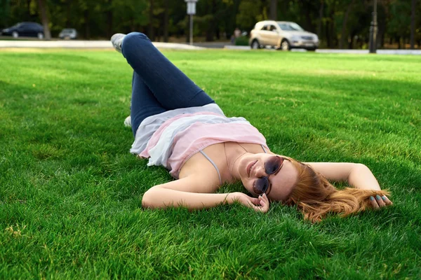 Glückliche Frau mit Brille im Gras liegend — Stockfoto