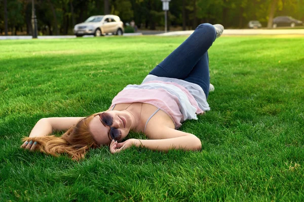 Happy woman with glasses lying on the grass — Stock Photo, Image