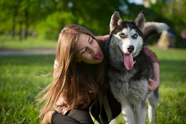 Девушка высунула язык так же, как и ее собака. — стоковое фото