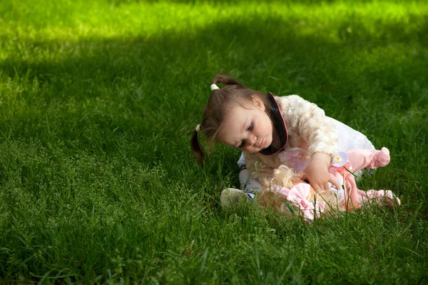 Ein kleines Mädchen spielt mit ihrer Puppe im Park — Stockfoto