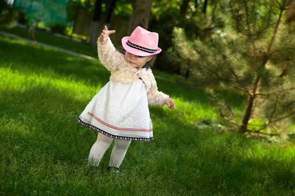 Ein kleines Mädchen mit Hut spielt im Park — Stockfoto