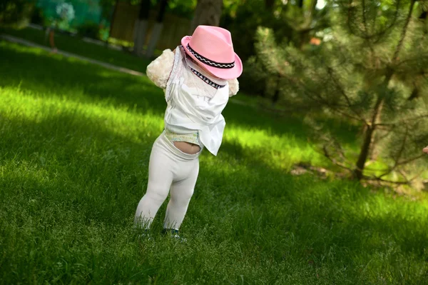 En liten flicka i en hatt som gömmer sig i sin klänning — Stockfoto