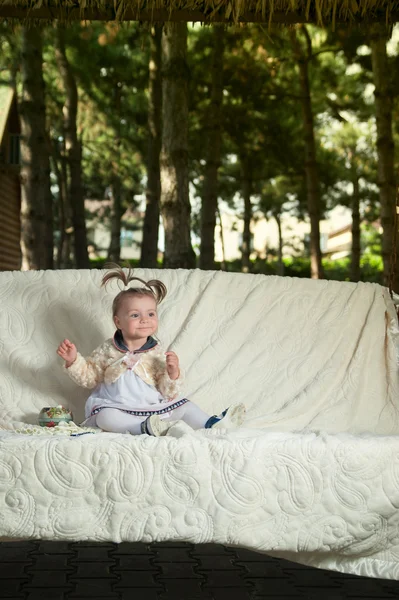 Ein kleines Mädchen amüsiert sich auf dem großen Sofa im Park — Stockfoto