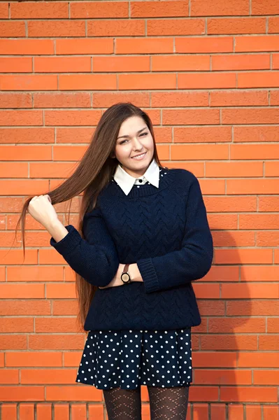 Jovem mulher endireita o cabelo em uma parede vermelha — Fotografia de Stock