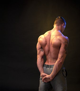 Karanlık bir arka plan üzerinde güzel fiziksel vücut geliştirmeci