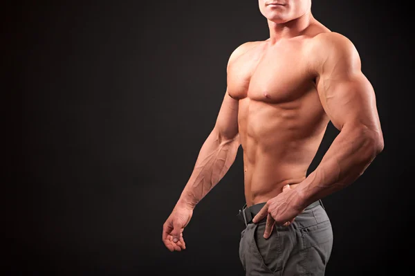 Beautiful physique bodybuilder on a dark background — Stock Photo, Image