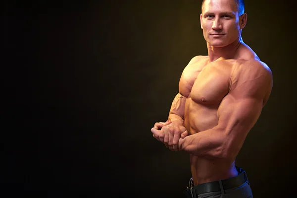 Kulturysta Wyświetlono biceps na ciemnym tle — Zdjęcie stockowe