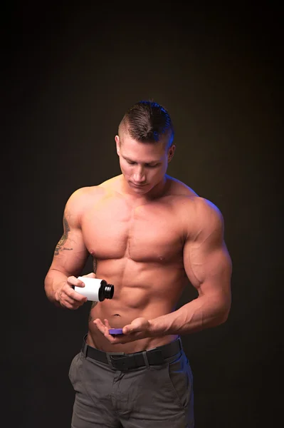 Strong bodybuilder uses nutritional supplements — Stock Photo, Image