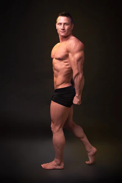 Culturista muestra músculos del tríceps sobre fondo oscuro — Foto de Stock