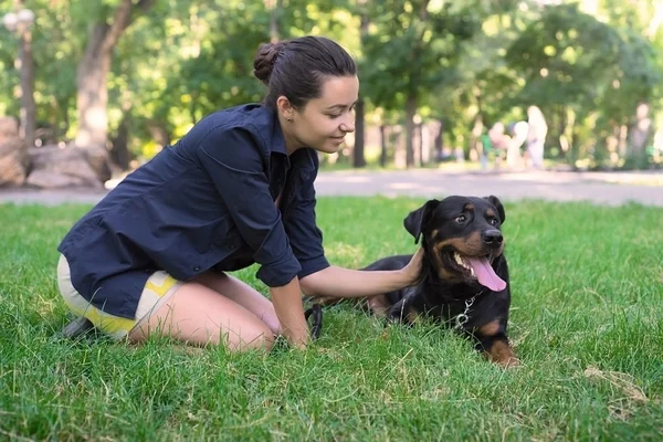 Hermosa mujer y rottweiler en un parque — Foto de Stock