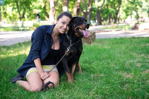 Portrait of a woman with her beautiful rottweiler lying outdoors — Stock Photo, Image