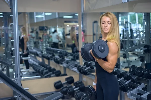 Vrouw schudt haar biceps op de sportschool — Stockfoto