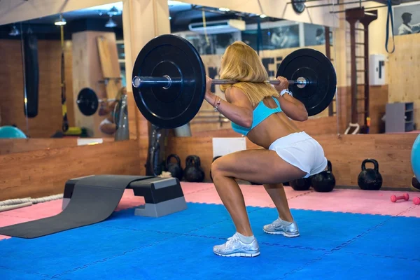 Kvinnor knäböj med en skivstång i gymmet — Stockfoto