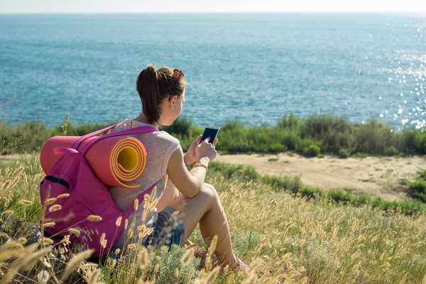 Mulher sentada na praia e gosta de telefone — Fotografia de Stock