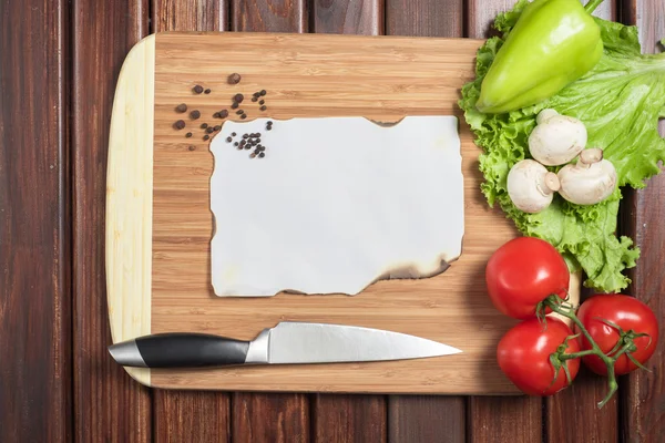 Овощи и бумага на кухонном столе — стоковое фото