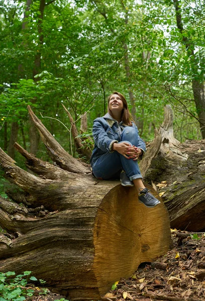 Kobieta siedzi na ścięte drzewo — Zdjęcie stockowe