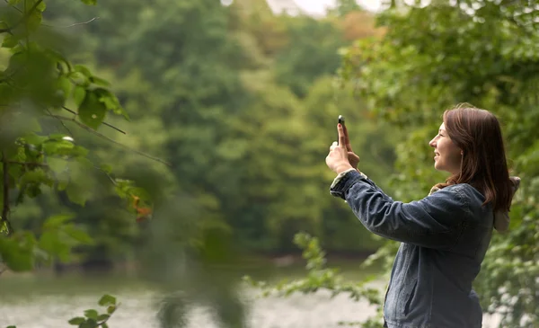 Mujer tomando fotos en la orilla del río — Foto de Stock