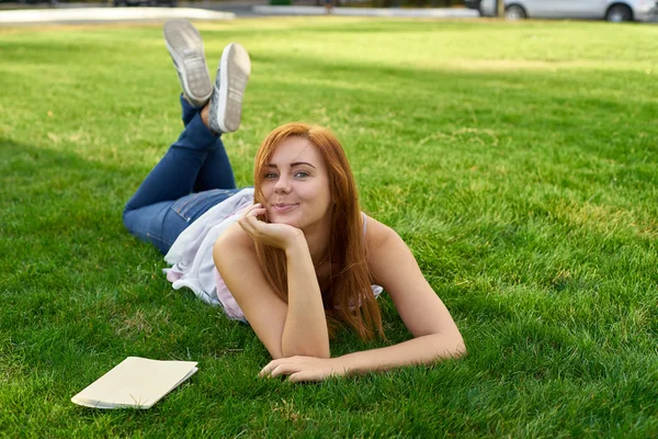 Frau liegt im Gras und erteilt Unterricht — Stockfoto