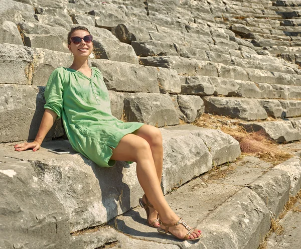 笑顔の女性は、コロッセオの廃墟の上に座っています。トルコ、Kem — ストック写真