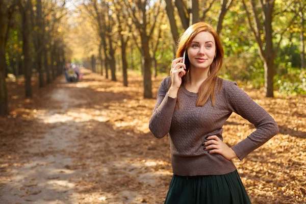 Woman talking on the phone in the autumn park — Stock Photo, Image