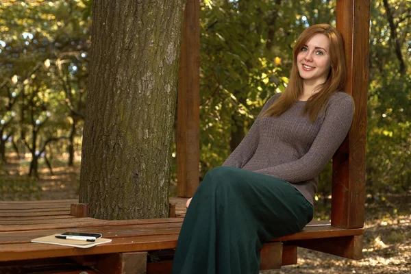 Femme heureuse assise dans le parc — Photo