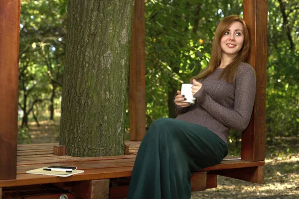 Jeune femme buvant du café dans le parc — Photo