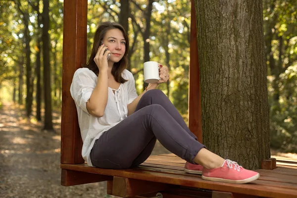 Mujer joven bebiendo café en el parque — Foto de Stock