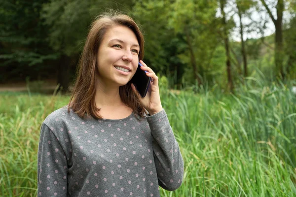 Happy young woman talking on the phone in the forest — Stock Photo, Image