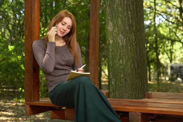 Giovane donna in un parco che parla al telefono — Foto Stock