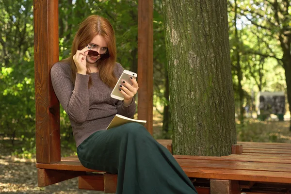 Mujer joven en un parque leyendo un mensaje — Foto de Stock